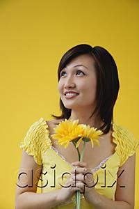 AsiaPix - Young woman holding yellow flowers, looking away