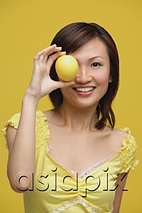 AsiaPix - Young woman holding lemon over her eye, portrait