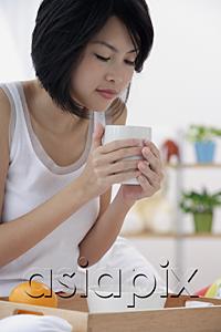 AsiaPix - Young woman having breakfast, holding coffee mug