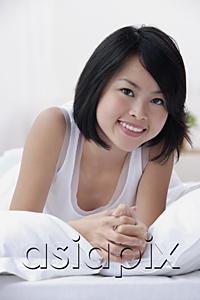 AsiaPix - Young woman on bed, smiling at camera
