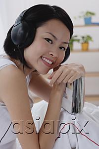 AsiaPix - Young woman wearing earphones, smiling at camera