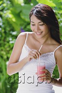 AsiaPix - Young woman holding drink, smiling, looking away