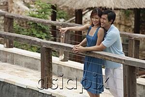 AsiaPix - Couple standing side by side on bridge, woman pointing in the distance