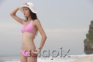 AsiaPix - Woman standing on beach, looking away, hand on head