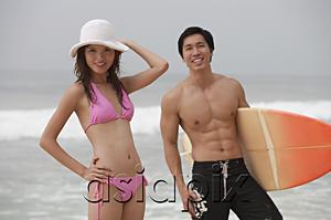 AsiaPix - Couple on beach, man carrying surfboard