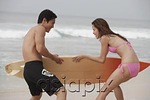 AsiaPix - Couple on beach, fighting for surfboard