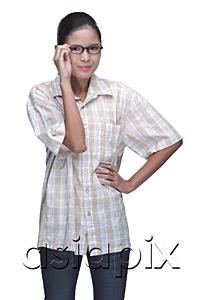 AsiaPix - Young woman adjusting eyeglasses, hands on hip