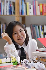 AsiaPix - Young woman in library, surrounded by books and crumpled paper