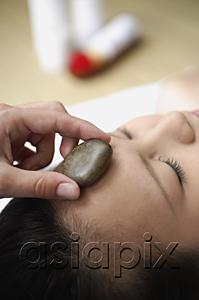 AsiaPix - Young woman in spa, massage stone being placed on her forehead
