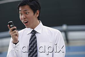AsiaPix - Businessman looking at mobile phone, making a face