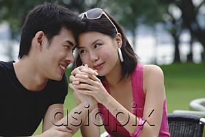 AsiaPix - Couple sitting side by side, face to face, holding hands