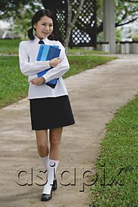 AsiaPix - Young woman in school uniform, walking on path, smiling at camera