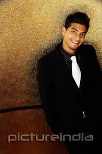 PictureIndia - Young man dressed in suit, looking up at camera