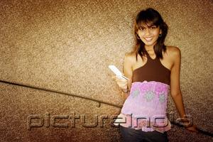 PictureIndia - Young woman holding mobile phone, smiling