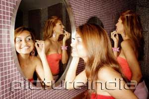 PictureIndia - Two women in public restroom, looking at mirror, applying make-up