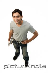 PictureIndia - Young man looking at camera, carrying books under arm