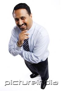 PictureIndia - Businessman smiling up at camera, arms crossed, hand on chin