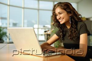 PictureIndia - Woman using laptop, smiling