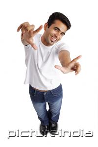 PictureIndia - Man smiling at camera, arm outstretched, making hand sign