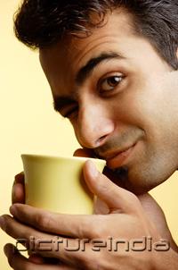 PictureIndia - Man holding mug close to face, winking