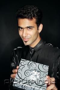 PictureIndia - Man holding present, looking at camera