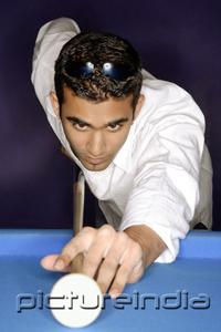 PictureIndia - Young man playing pool, portrait
