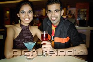 PictureIndia - Couple in a club with drinks, smiling at camera