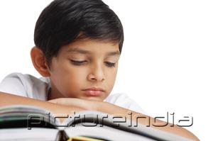 PictureIndia - Boy reading book, leaning on hand