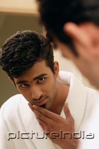 PictureIndia - Man looking in mirror, touching his chin