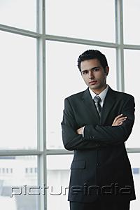 PictureIndia - Young businessman arms crossed, looking at camera