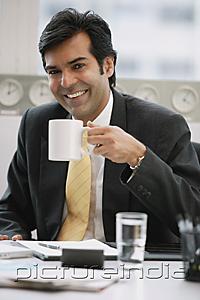 PictureIndia - Businessman in office holding mug, smiling