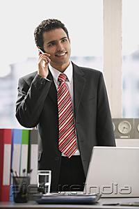 PictureIndia - Businessman standing in office, using mobile phone