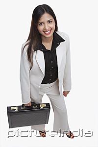 PictureIndia - Businesswoman looking at camera, carrying briefcase