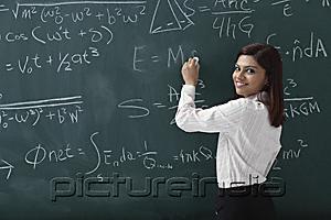 PictureIndia - Woman writing equations on chalk board