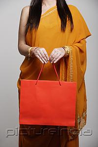 PictureIndia - Cropped shot of woman wearing sari holding orange shopping bag