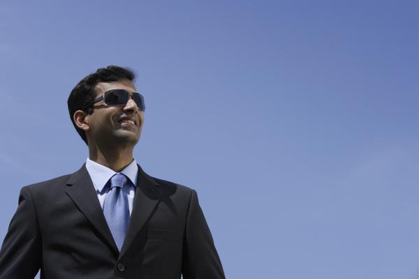 PictureIndia - Indian businessman wearing sunglasses and smiling outside.