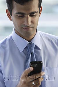 PictureIndia - Head shot of Indian businessman reading text messages.