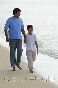 PictureIndia - Father and son holding hands and walking down the beach.