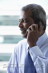 PictureIndia - Head shot of mature Indian business man talking on phone