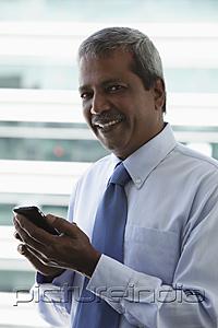 PictureIndia - Head shot of mature Indian man holding hand phone