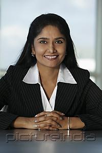 PictureIndia - Indian business woman sitting at desk with hands folded