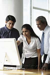 PictureIndia - Indian woman looking at a computer with male colleagues