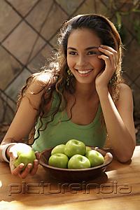 PictureIndia - Young woman with a bowl of green apples smiling