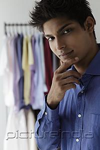 PictureIndia - young man looking at camera with shirts in background