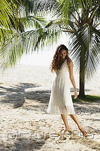 PictureIndia - young woman walking in the sand with coconut trees in background