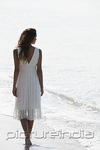 PictureIndia - back view of woman wearing a white dress and walking a long the beach