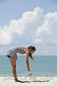 PictureIndia - young woman picking up rubbish on the beach