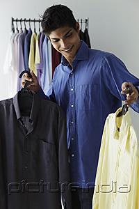 PictureIndia - young man looking at two shirts
