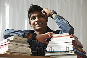 PictureIndia - young man with a stack of books smiling and thinking