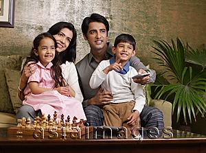 Asia Images Group - family sit on couch, chess set, big plant